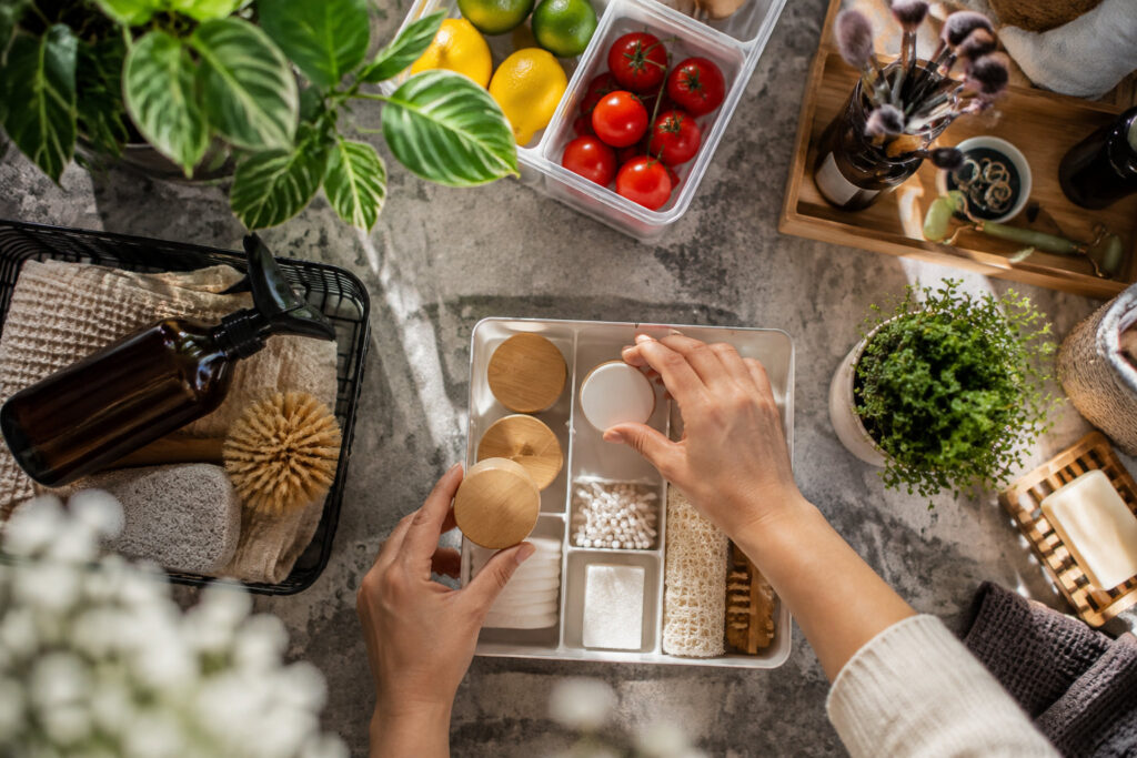 Mains rangeant des produits cosmétiques zéro déchet dans un organisateur compartimenté sur une table en pierre.